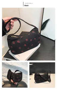 Détail d'un sac à bandoulière en velours noir avec broderie de fraises et fermeture éclair