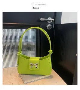 Detail of green small square underarm bag with silver metallic bow buckle and knotted handle