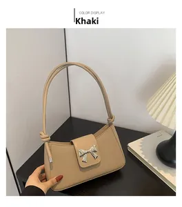 Detail of khaki leather shoulder bag featuring silver butterfly hardware and knot strap