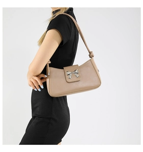 Detail of apricot shoulder bag featuring a silver butterfly buckle and knot strap detail