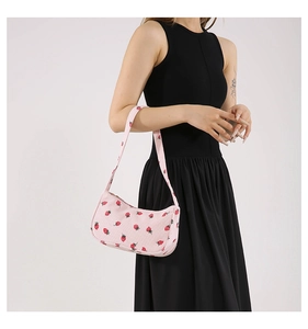 Vue détaillée d'un sac d'épaule en velours côtelé rose avec motif fraise sur robe noire