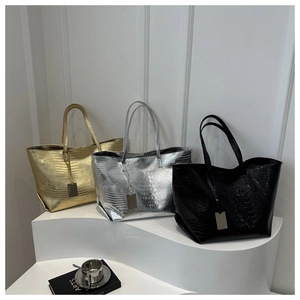 Detailed display of gold, silver and black crocodile-patterned tote bags on a podium