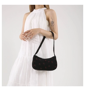 Détail du sac croissant en velours noir avec imprimé fraises porté par un mannequin