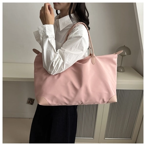 Detail showing the reinforced leather corners and pink waterproof nylon fabric of the tote bag