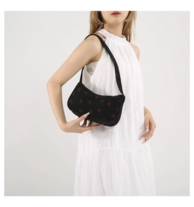 Sac bandoulière en velours côtelé noir à motif fraise porté par un mannequin