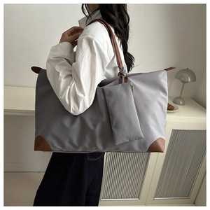 Detail of grey waterproof Oxford tote bag with brown leather handles and side pouch
