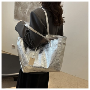 Silver crocodile embossed tote bag with thin straps worn by a model in a minimal studio