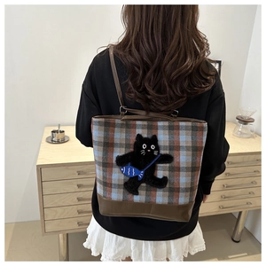 Vue détaillée de dos d'un modèle portant un sac cabas à carreaux avec patch chat noir