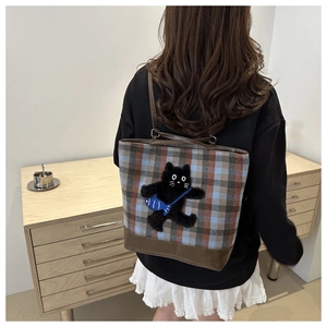 Détail du sac cabas à carreaux avec écusson de chat noir et lanières en cuir marron