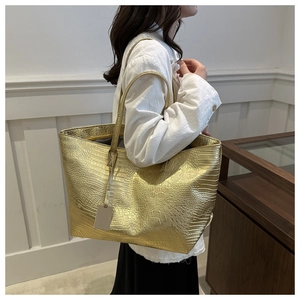 Detailed close-up of large tote bag with gold crocodile pattern texture and shoulder strap
