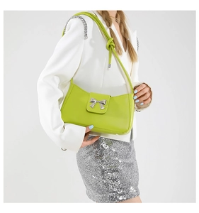 Detail of neon green shoulder bag with silver butterfly buckle and knotted strap design