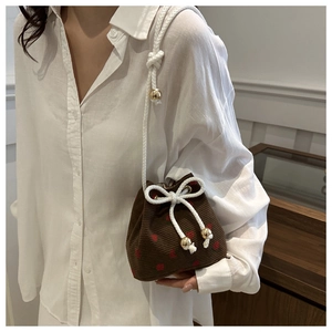 Detail of brown corduroy bucket bag with red heart pattern and rope shoulder strap
