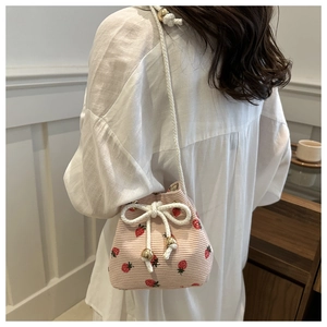 Detail of pink strawberry print corduroy bucket bag with drawstring and gold beads