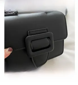 Détail d'un sac à main noir mat avec une grande boucle élégante sur le rabat de fermeture