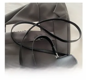 Détail de la bandoulière réglable et de la boucle métallique sur un sac à main noir