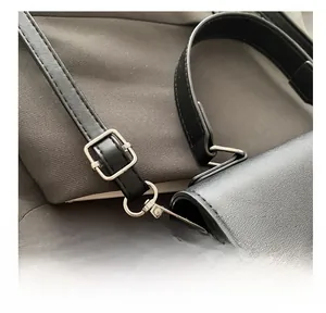 Détail d'une bandoulière réglable en cuir noir avec boucle argentée et fermoir mousqueton