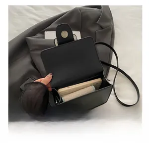 Vue intérieure d'un sac bandoulière en cuir noir avec téléphone et cosmétiques