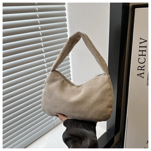 Detail of corduroy shoulder bag showing vertical ribbed texture and zip closure