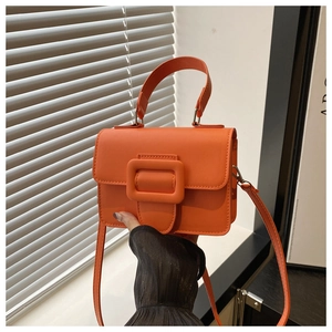 Detailed shot of an orange PU leather crossbody bag with minimalist square buckle feature