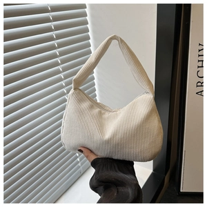 Detail of soft cream corduroy shoulder bag with vertical ribbed texture and crescent shape