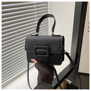 Detail of black minimalist handbag with large square buckle and matte leather texture