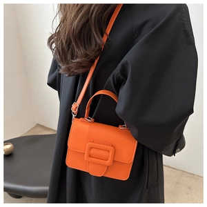 Gros plan du sac en cuir verni orange vif avec boucle carrée élégante et poignée supérieure