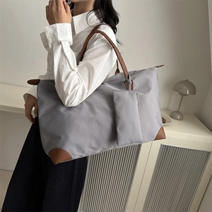 Grey large capacity nylon tote bag with leather handles shown in a modern urban interior