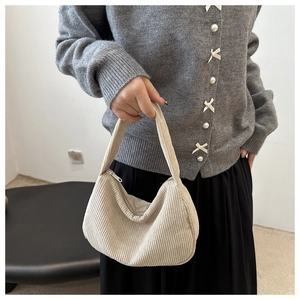 Close-up of cream corduroy shoulder bag showing vertical texture and wide handle