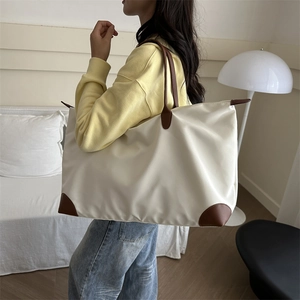 Large beige nylon tote bag with brown leather handles and base for daily travel and commuting