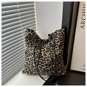 Detail of leopard print canvas tote bag featuring black leather straps and metal eyelets