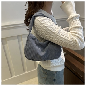 Close-up of blue corduroy shoulder bag showing vertical rib texture on white backdrop