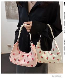 Detail of strawberry print corduroy underarm bags with elegant faux pearl handles