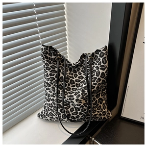 Detail of the leopard print canvas tote bag featuring premium black leather shoulder straps