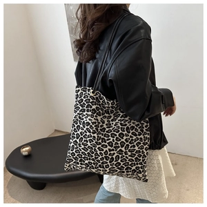 Detail of large leopard print tote bag with slim black straps on a minimalist background