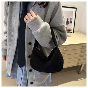 Detail of black corduroy shoulder bag showing vertical texture and zipper closure