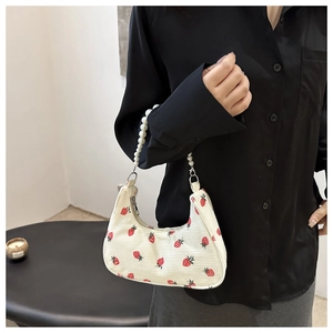 Detail of corduroy hobo bag with strawberry print and elegant pearl chain handle