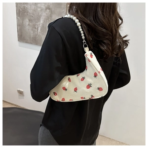 Detail of cream corduroy shoulder bag with strawberry print and pearl chain strap