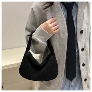 Detail shot of black corduroy shoulder bag with silver zipper and soft textured fabric