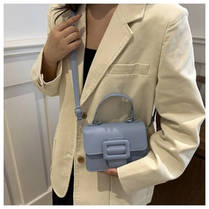 Gros plan du mini sac carré bleu clair porté par un mannequin, montrant les détails