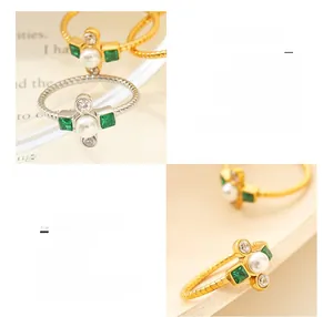 Detail of 18K gold plated cross ring featuring green crystals and twist band design