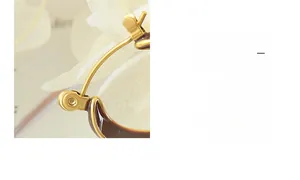 Nahaufnahme der goldenen V-förmigen Creolen mit dunkelbraunem Emaille-Finish im Retro-Stil