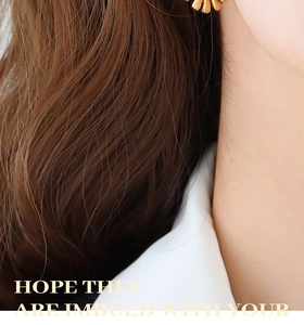 Detail of vintage gold twisted earrings with a sunburst pleated disc on a female model