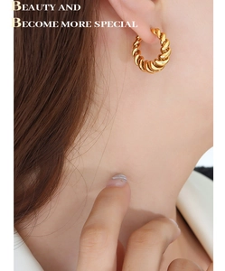 Close-up of twisted croissant earrings in 18K gold finish on a model for a chic look
