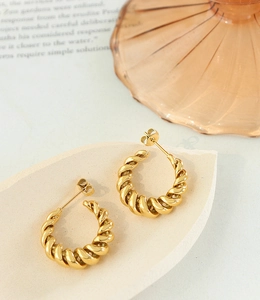 Macro shot of French style gold croissant hoop earrings with twisted texture details
