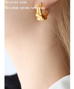 Gros plan de boucles d'oreilles vintage en acier titane doré style lave sur un mannequin