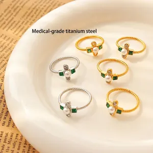 Baroque titanium steel rings with pearls and green crystals on a ceramic tray