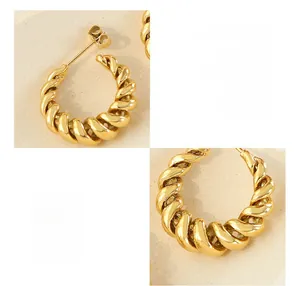Macro detail of twisted texture on gold brass C-shaped hoop earrings with metal backs
