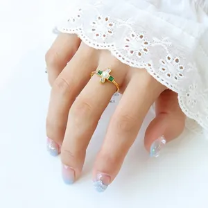 French style gold plated ring with pearls and green gems worn on a hand with lace