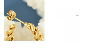 Detailed macro view of gold-plated C-shaped earrings with spiral twisted texture design