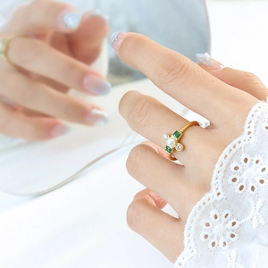 Baroque pearl ring with green crystals on a gold twisted band shown on a mirror
